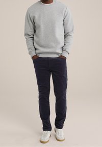 Šedá bavlněná mikina s kulatým výstřihem, v kombinaci s námořnickýma kordovým kalhotama a bílými teniskami s hnědými podrážkami.