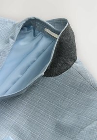 Hellblau gemustertes Hemd mit einem weichen Innenkragen und einem kontrastierenden dunkelgrauen Außenkragen. Glattes Gewebe mit strukturiertem Design.