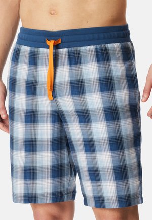 Torace maschile che indossa pantaloncini blu a quadri con una cintura elastica e un laccio arancione, su uno sfondo bianco.
