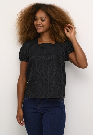 Zwarte top met een getextureerd takkenpatroon, vierkante halslijn en pofmouwen, gecombineerd met donkerblauwe jeans. Gladde stof met een subtiele glans.