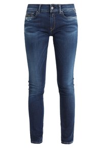 Pantalones vaqueros ajustados en denim azul oscuro, con un clásico diseño de cinco bolsillos, un sutil desvanecimiento y cierre de botón. Textura suave con detalles de costura.