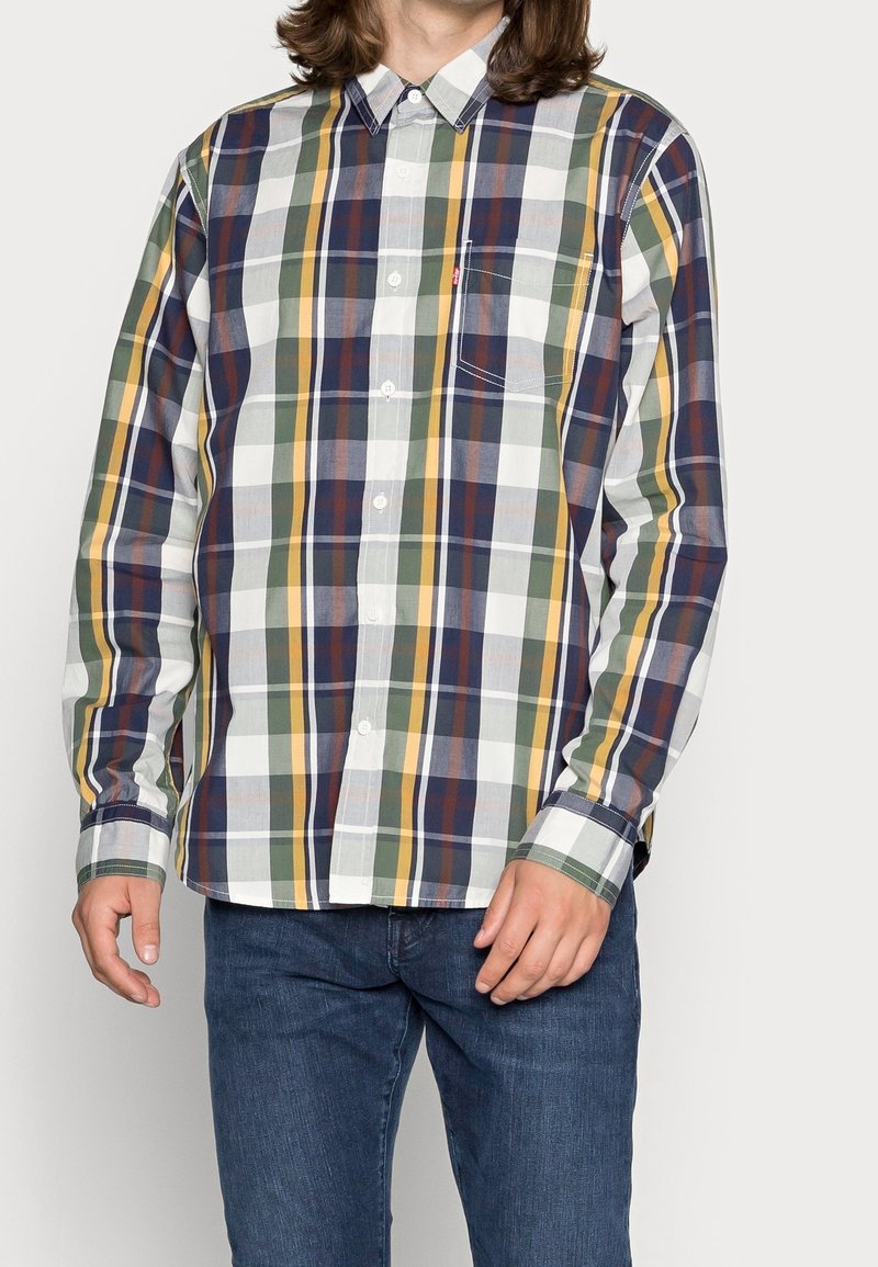 Camicia a maniche lunghe a quadri in verde, blu navy e giallo, realizzata in cotone. Presenta un colletto a punta e una tasca sul lato sinistro del petto.