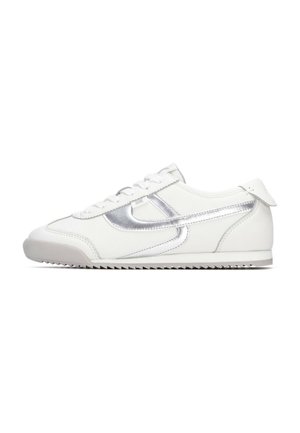 Zapatilla deportiva de cuero blanco con detalles metálicos plateados, laterales texturizados, cordones planos, punta redondeada y suela de goma duradera con patrón antideslizante.