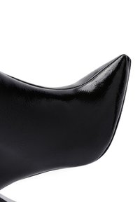 Scarpa nera a punta, realizzata in materiale lucido, con una silhouette elegante e una texture liscia, arricchita da sottili dettagli di cucitura lungo i bordi.