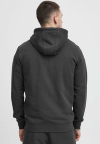 Hoodie gris foncé avec poche kangourou, poignets et ourlet côtelés. Dispose d'une capuche doublée et d'une texture lisse et douce.