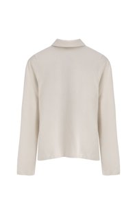 Jasnobeżowa koszula z długim rękawem o gładkiej fakturze, z złożonym kołnierzykiem i luźnym krojem, bez widocznych wzorów ani akcentów.