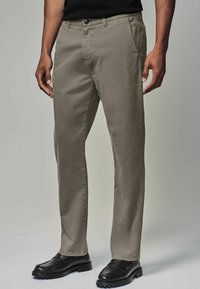 Helle graue Chinos mit einer glatten Textur, geradem Bein design und vorderen Taschen, kombiniert mit schwarzen Slippers.