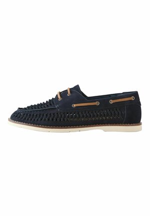 Navy blue woven leather loafer with tan laces threaded through eyelets, white sole, and moccasin-style stitching on a white background.