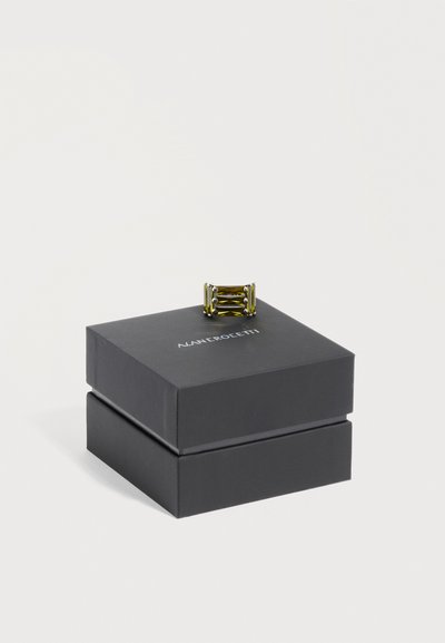 Bague géométrique en or présentée sur une boîte à bijoux noire fermée Alan Crocetti avec un fond blanc uni.