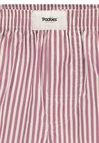 Pantaloni corti rigati rosa e crema con una vita elasticizzata e un dettaglio di tasca cucita. L'etichetta riporta "Pockies Couch Couture."
