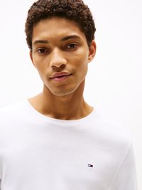 Biała long-sleeve koszulka wykonana z bawełny, z małym haftowanym logo po lewej stronie klatki piersiowej. Prosty design z okrągłym dekoltem.