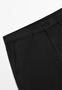 Zwarte katoenen broek met een gladde textuur, rechte snit en een voorste sluiting met een knoop. Voorzien van ceintuurlussen en zijzakken.