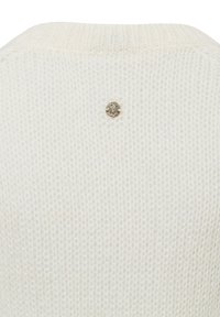 Zacht wit gebreid stof met een klein rond zilveren embleem met een reliëfontwerp in het midden.