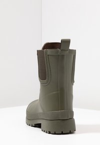 Gumové kotníkové boty v tmavě zelené barvě s texturovanými bočními panely, zesílenou patou a zubatou podrážkou pro lepší trakci. Design s kulatou špičkou.