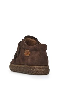 Scarpa in suede marrone con finitura testurizzata, caviglia bassa e un piccolo tag in pelle sul tallone con un logo impresso. Suola in gomma.