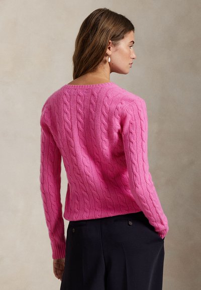 Rosa kabelstrikket genser med lange ermer og vid utringning; har teksturerte mønstre og en tettsittende silhuett.