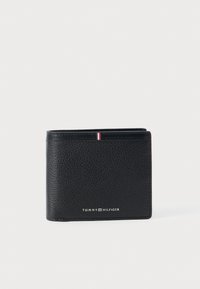 Carteira de couro preto com um acabamento texturizado. Apresenta uma pequena faixa de destaque nas cores vermelho, branco e azul, e o logotipo "TOMMY HILFIGER". Design dobrado.