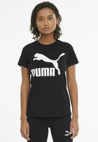 Czarny bawełniany t-shirt z dużym białym logo Puma i wyraźnym tekstem. Krótkie rękawy i okrągły dekolt. Gładka tekstura, casualowy krój.
