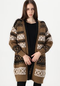 Cárdigan de punto marrón con patrones geométricos en blanco y negro, de frente abierto, corte holgado y puños acanalados. Textura suave y cálida.