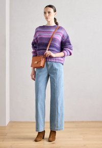 Lila és rózsaszín csíkos kötött pulóver, világoskék bő szabású farmernadrág, barna sarkú bokacsizma és egy kicsi barna crossbody táska.
