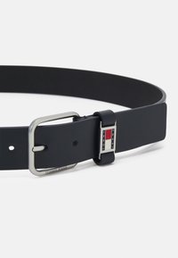 Cintura nera in materiale sintetico liscio, con una fibbia rettangolare argentata e un accento di marca con dettagli rossi e bianchi.