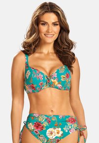 Kostium kąpielowy w kwiatowy wzór na turkusowym tle. Górna część ma regulowane ramiączka oraz wiązanie, a dolna część posiada akcenty w postaci wiązań po bokach.