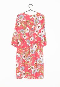 Röd blommig klänning med trekvartslånga ärmar, åtsittande midja och en mängd vita och blå blommor med gröna detaljer.