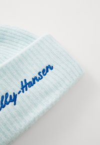 Lichtblauwe gebreide beanie met een geribbelde textuur en een omgeslagen rand, met daarin donkerblauwe borduurtekst "Helly-Hansen."