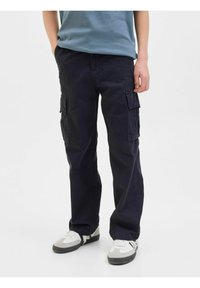 Pantalon cargo bleu marine avec plusieurs poches latérales, design à jambes droites, en tissu coton. Assorti avec des baskets blanches et grises.