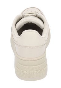 Krémově zbarvená teniska s hladkým koženým špičkou a strukturovaným látkovým patem. Má gumovou podrážku a na zadní straně je vyraženo "TOMMY JEANS".