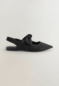 Bailarinas de ante negro con talón descubierto y punta afilada, con un detalle de nudo en la parte delantera y suaves pliegues en los laterales. Suela plana.