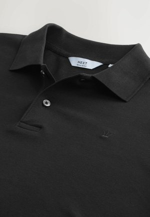 Polo noir en tissu texturé avec un col, deux boutons et un petit logo de couronne brodé sur la poitrine. Coupe standard.