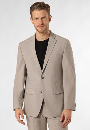 Beige Blazer aus strukturiertem Stoff, einreihiges Design, mit Reverskragen, zwei Vordertaschen und taillierter Passform. Getragen über einem schwarzen Hemd.