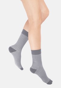 Graue Knöchelsocken mit einem strukturierten Zickzackmuster, kontrastierenden dunkelgrauen Bündchen und verstärkten Fersen, die ein modernes Design präsentieren.