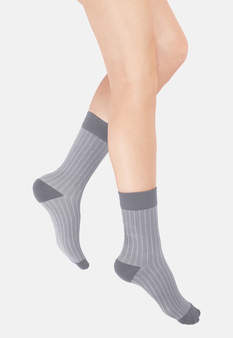 Graue Knöchelsocken mit einem strukturierten Zickzackmuster, kontrastierenden dunkelgrauen Bündchen und verstärkten Fersen, die ein modernes Design präsentieren.