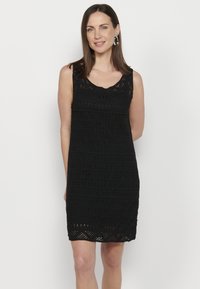 Abito nero senza maniche con un design in crochet testurizzato, caratterizzato da un scollo e un orlo ondulati. Tessuto a motivo con trama aperta e righe.