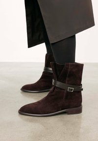 Burgundi velúr bokacsizmák fekete bőrszíjjal és fém csattal, sima kerek orral és alacsony fasarkal.