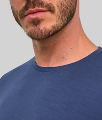 Maglietta a maniche corte di colore blu navy con scollatura rotonda, realizzata in tessuto liscio e caratterizzata da una sottile trama. In primo piano si vede il collo e il viso di un modello.