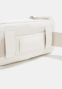 Bolso de cuero blanco con una textura suave, con cierre de cremallera y correa de tela beige. Incluye un parche rectangular en el lateral.
