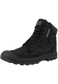 Botas impermeables negras que presentan una combinación de materiales de ante y malla, diseño con cordones, cuello acolchado y suela de goma resistente.