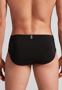 Černé plavkové šortky vyrobené z hladkého materiálu, s jednoduchým designem, středně vysokým pasem a bezpečným pasem s logem.