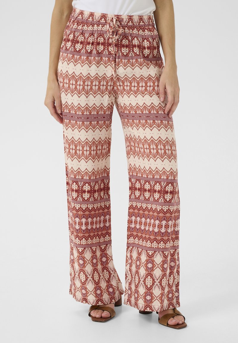Pantalons larges en rouge et crème avec un motif géométrique, dotés d'une taille élastique et d'un cordon de serrage. Fabriqués en tissu léger.