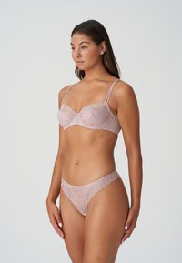 Koronkowy stanik i stringi w delikatnym odcieniu różu, z kwiatowymi wzorami, regulowanymi ramiączkami i falbaniastymi krawędziami dla subtelnego wykończenia.