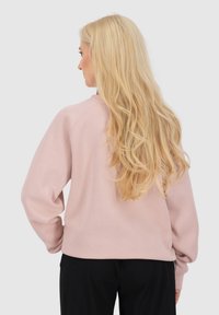 Roze sweatshirt met een relaxte pasvorm, raglan mouwen en een zachte textuur. Beschikt over een ronde halslijn en subtiele stikdetails.