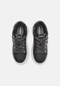 Schwarze Sneakers mit einem Obermaterial aus glattem Leder, ausgestattet mit klobigen weißen Sohlen, strukturierten schwarz-weißen Schnürsenkeln und silbernen Hardware-Akzenten.