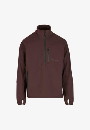 Burgundy pullover-takki sileässä kankaassa, jossa on korkea kaulus, vetoketjullinen rintatasku, sivuvetoketjut ja peukalonreiät hihansuissa.