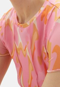 Top de manga corta con un patrón ondulado en tonos rosas y naranjas, hecho de una tela ligera y transpirable con un escote redondo.