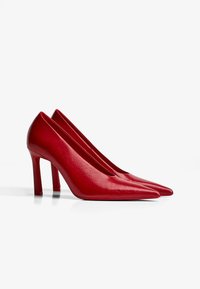 Pantofi cu toc înalt din piele roșie, cu un design cu vârf ascuțit și textură netedă. Prezintă o siluetă elegantă și un toc stiletto rezistent.