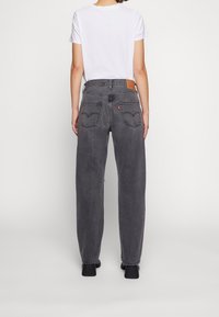 Grå denimjeans med lös passform, hög midja och bakfickor med en brun läderlapp med röda logotillbehör.