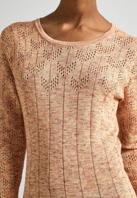 Stickad långärmad tröja i ljus persika med ett strukturerat mönster av vertikala linjer och hjärtan, med rund halsringning och ribbade kanter.